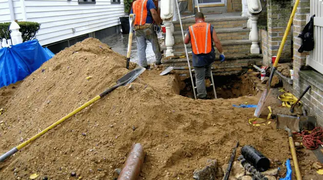 Contractors performing foundation protection and exterior drainage excavation near residential home steps in Pittsburgh, PA